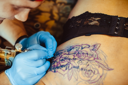 tattooer showing process of making a tattoo, hands holding a tatoo machineの写真素材