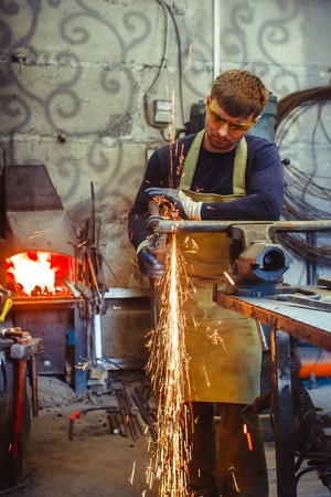Craftsman sawing metal sparkles all around workshop. Working at noon.の写真素材