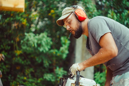 Portrait of lumberjack logger worker in protective workwear with chainsaw at forestの写真素材