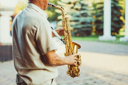 Novokuzneck, Russia, 16.07.2017: sax musician walking in the street during a celebration on blur backgroundのeditorial素材