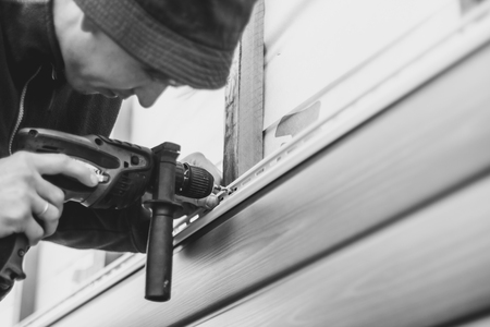 A worker installs panels beige siding on the facade of the houseの写真素材