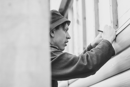 A worker installs panels beige siding on the facade of the houseの写真素材