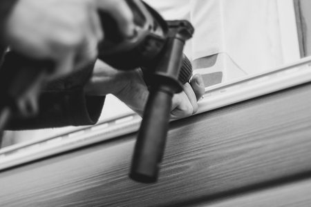 A worker installs panels beige siding on the facade of the houseの写真素材