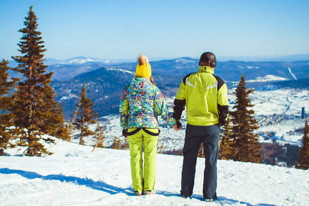 Rear view of skiers on ski slope with mountains in background. Horizontal shot.の写真素材