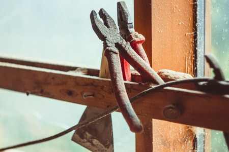 Old pliers on a wooden bar, around sawdust. Tools for construction and repair