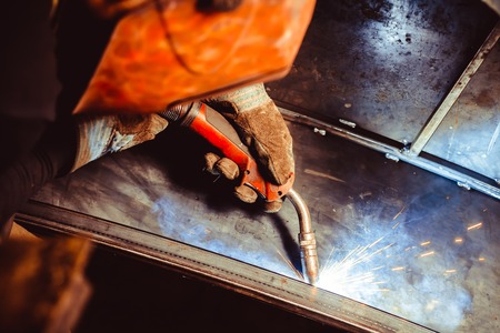 worker welding metal with sparks and smoke in the helmet