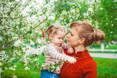 Close up portrait of a joyful mother and daughter relaxing together in a beautiful spring field of grass and flowers, hugging and enjoying a sunny holiday outdoors. Family love and lifestyle.の写真素材