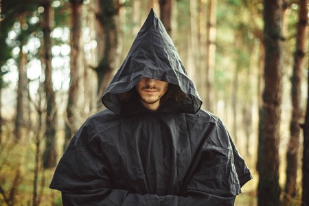 A creepy man in a black hood in the forestの写真素材