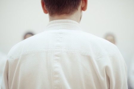 Young sporty man in kimono on light backgroundの写真素材