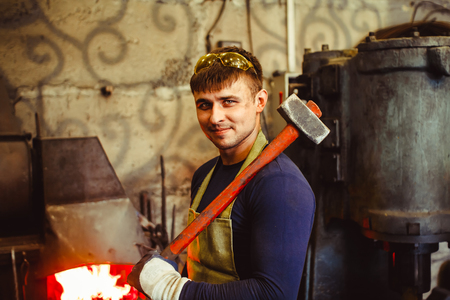 two forge are in working clothes in the forgeの写真素材