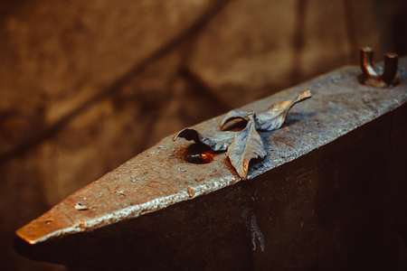 Forged metal rose lying on the pier in the smithy behind the fireの写真素材