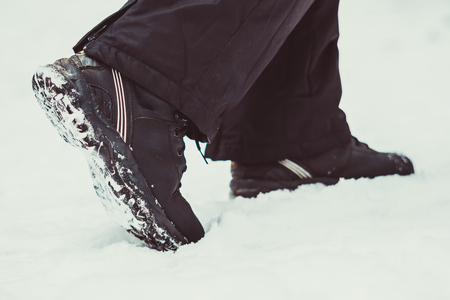 fitness, sport, people, footwear and healthy lifestyle concept - close up of male feet running along winter road and snowの写真素材