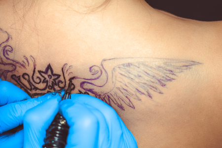 tattooer showing process of making a tattoo hands holding a tatoo machineの写真素材