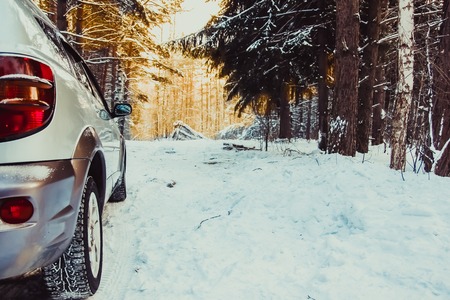 Car tires on winter road covered with snow. Vehicle on snowy alley in the morningの写真素材