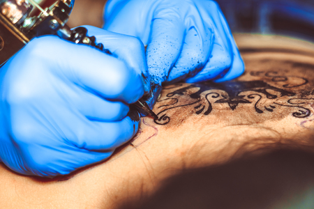tattooer showing process of making a tattoo hands holding a tatoo machineの写真素材