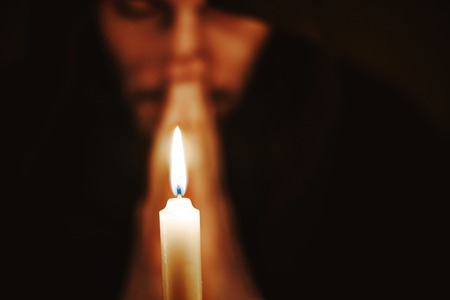 the monk in the dark over the candle idly by