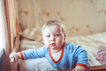 baby playing with his feet on the bed at home