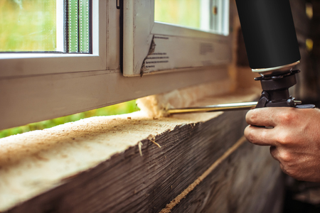 Applying polyurethane foam. Detailed view on process of installing a polyvinyl window. Working for a construction company.の写真素材