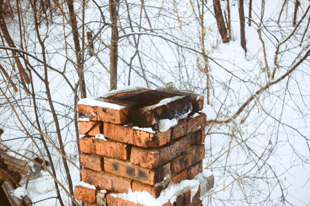 Chimney in red bricks with white snow on roof.の写真素材