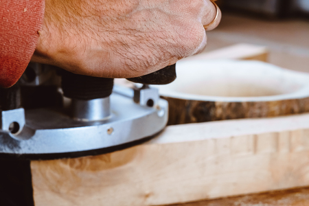 Processing of a furniture part by a machine for polishing a tree. the grinding machine on a board, selective focus. Process of processing the edges of a furniture product in side viewの写真素材