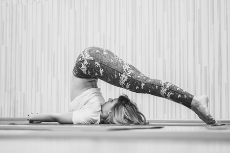 Beautiful girl in sportswear is doing yoga on yoga mat in sports hallの写真素材