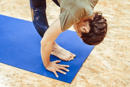 Beautiful girl in sportswear is doing yoga on yoga mat in sports hall