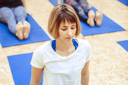 Beautiful girl in sportswear is doing yoga on yoga mat in sports hallの写真素材