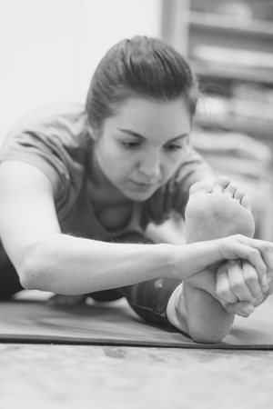 Beautiful girl in sportswear is doing yoga on yoga mat in sports hallの写真素材