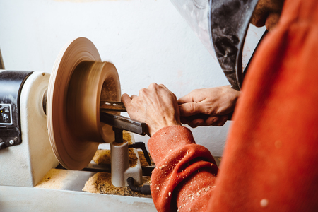 the worker turns the wood on a lathe in his workshopの写真素材