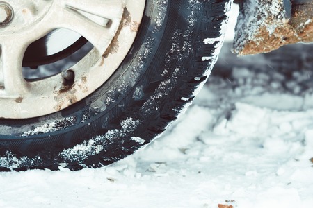 Closeup of car tires in winter on the road covered with snowの写真素材