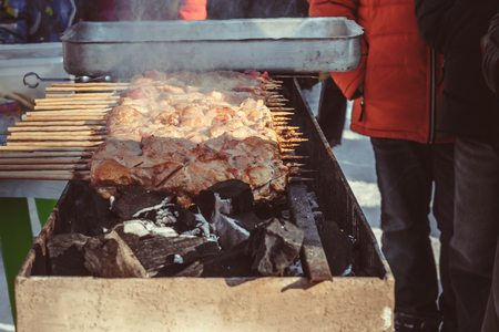 Fried pieces of meat, cooking on a metal skewer. The fried meat is made in barbecue. On charcoal. Street food.の写真素材