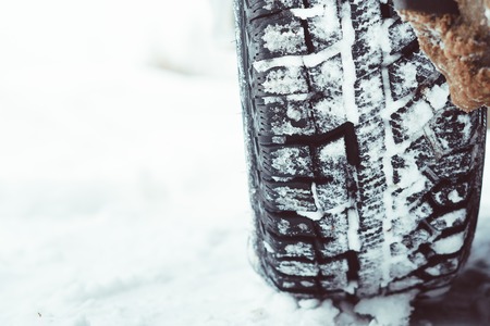 Closeup of car tires in winter on the road covered with snowの写真素材