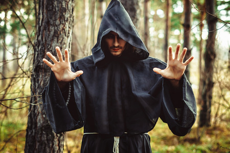 the black monk pointing his finger in the woodsの写真素材