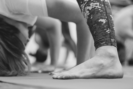 Beautiful girl in sportswear is doing yoga on yoga mat in sports hall