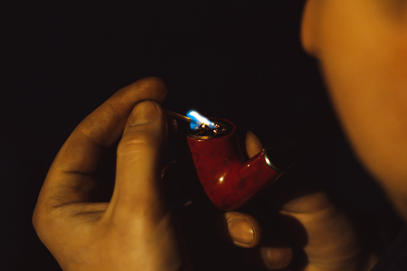 man Smoking pipe at night in the light of a lanternの写真素材