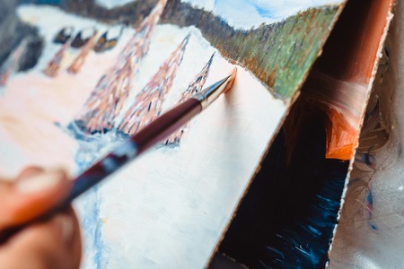 artist paints a picture of oil paint brush in hand with palette closeupの写真素材