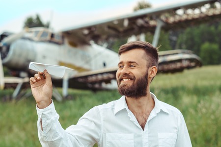 a man on the background of an old plane lets paper airplanes sitting on the grassの写真素材