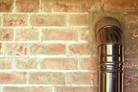 iron pipe of the fireplace of the house in a brick wall