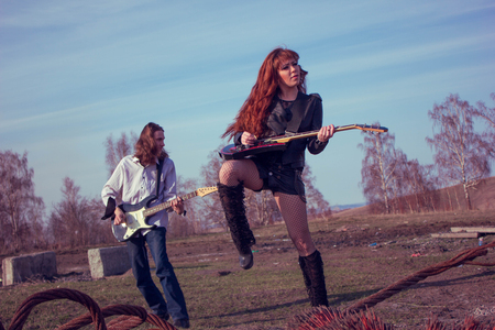 guy with girl playing rock on guitars shaking her hairの写真素材