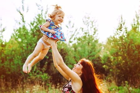 mom picks up daughter on arms laughing upの写真素材
