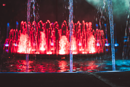 Colored water fountain at nightの写真素材