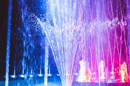 Colored water fountain at nightの写真素材