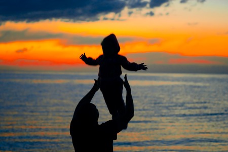 Father and son playing on the beach at the sunset time. Concept of friendly family.の写真素材