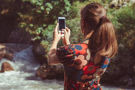 girl shoots a mountain river on her phoneの写真素材