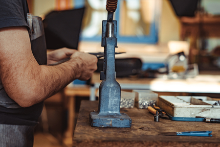Man works in carpentry workshop. He fixes wooden handle in vice. Different tools are on workbench. Men at work. Hand work.の写真素材