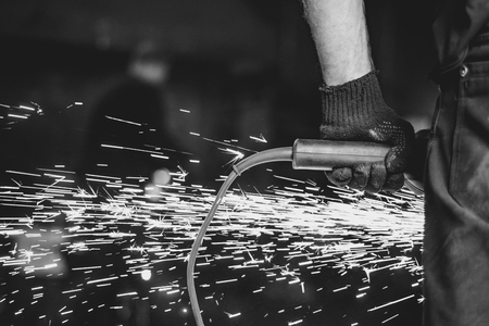 Craftsman sawing metal sparkles all around workshop. Working at noon.の写真素材