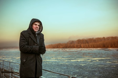 the guy freezes in a coat in the winter on the streetの写真素材