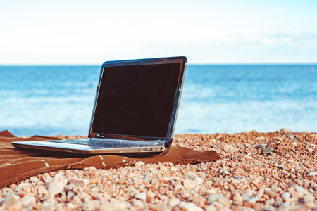 laptop on the sand on a blanket by the seaの写真素材