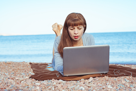 Young woman using laptop computer on a beach. Freelance work conceptの写真素材
