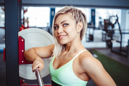 Sporty woman standing with arms crossed in fitness gym.